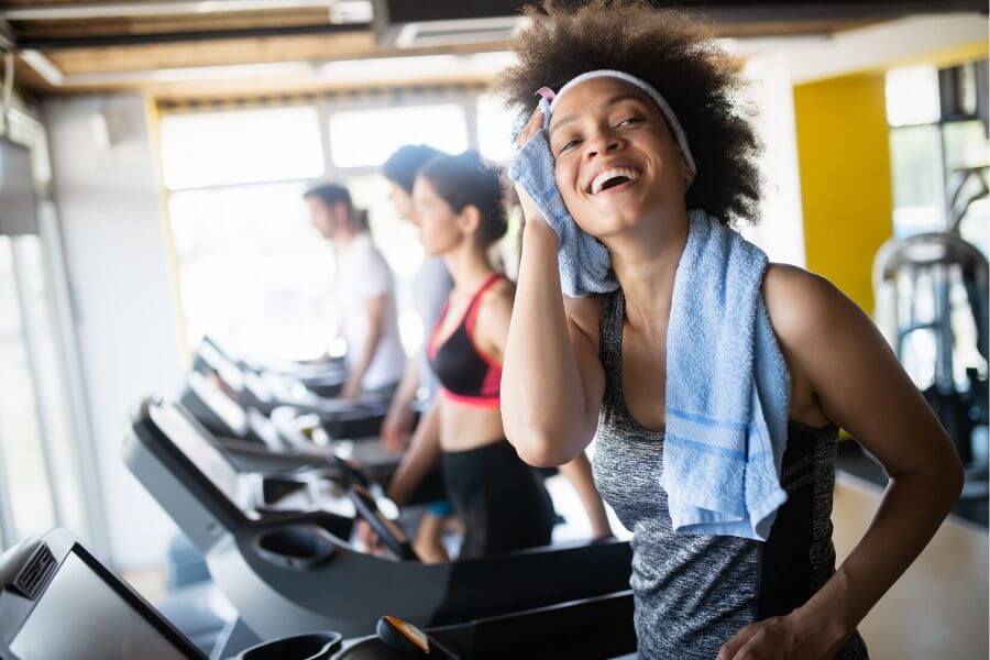 Lady wipes sweat on treadmill in commercial gym